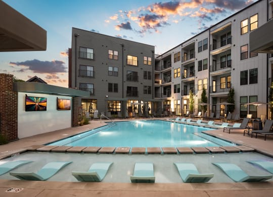 an apartment complex with a swimming pool and chaise lounge chairs at Abberly Riverwalk Apartment Homes, Nashville, TN