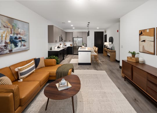 a living room with a brown couch and a coffee table in front of a kitchen with a  at Abberly Riverwalk Apartment Homes, Nashville, Tennessee
