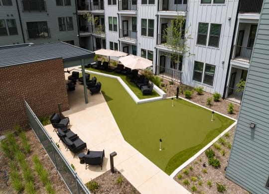 an outdoor lounge area with umbrellas and tables in front of an apartment building at Abberly Riverwalk Apartment Homes, Tennessee
