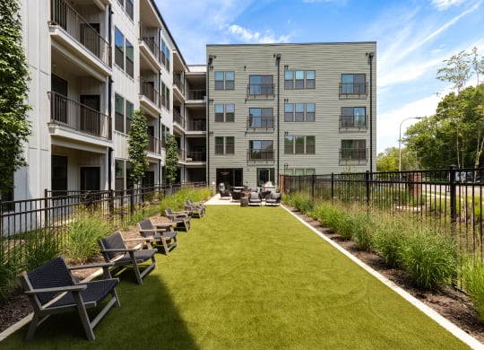 a grassy area with lounge chairs and a fire pit in the middle of an apartment complex at Abberly Riverwalk Apartment Homes, Tennessee