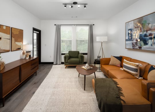 a living room with a brown couch and a green chair  at Abberly Riverwalk Apartment Homes, Tennessee, 37228