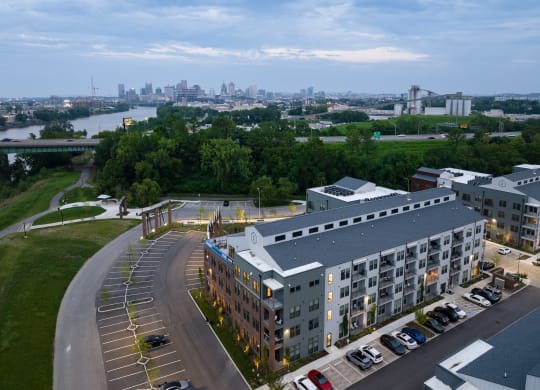 a large building with a parking lot in front of it and a city in the background at Abberly Riverwalk Apartment Homes, Nashville, 37228