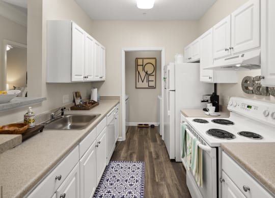 a kitchen with white cabinets and a white stove top oven  at Abberly Grove Apartment Homes, Raleigh, NC