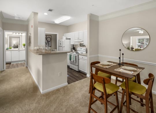 a dining area with a table and chairs and a kitchen in the background at Abberly Grove Apartment Homes, Raleigh, 27610