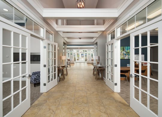 a long hallway with white doors and tables and chairs
