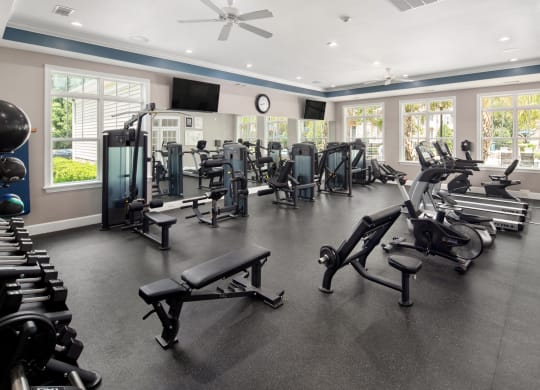 the gym has a large amount of exercise equipment and windows