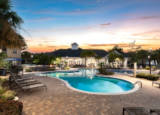 a swimming pool at sunset with a building in the background