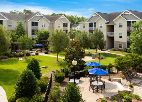 an outdoor patio area with tables and umbrellas in front of an apartment complex