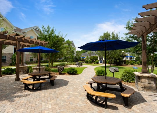 a patio with picnic tables and umbrellas in a park