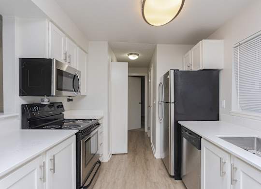 A kitchen with black appliances and white cabinets.