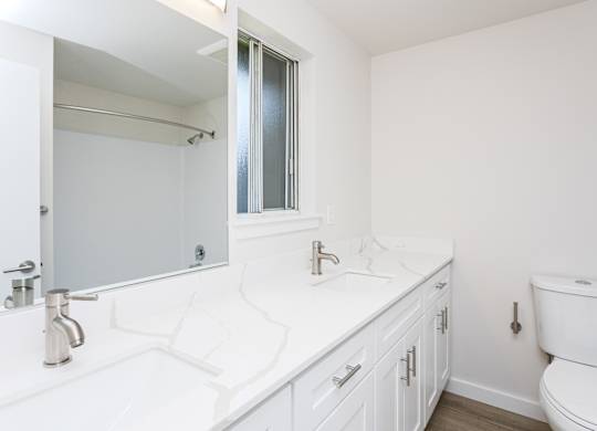A white bathroom with a toilet, sink, and mirror.