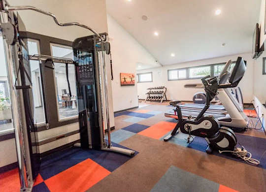 A gym with a variety of equipment including a treadmill, a stationary bike, and a weight machine at Altitude Apartment, Tacoma, WA, 98444