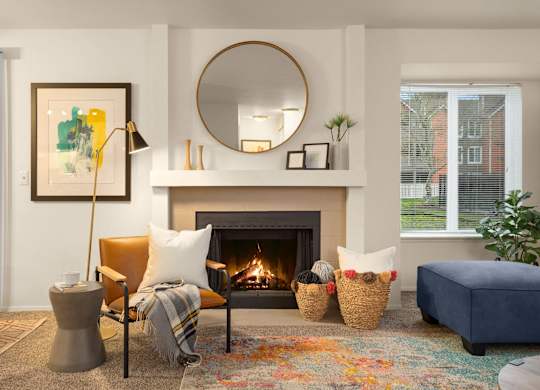 A living room with a fireplace, a chair, a couch, and a painting on the wall.