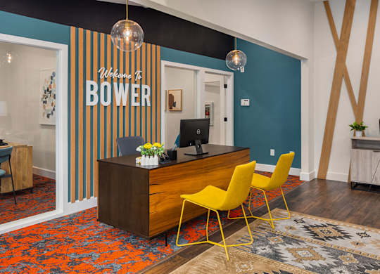 A reception area with a desk and chairs in front of a sign that says
