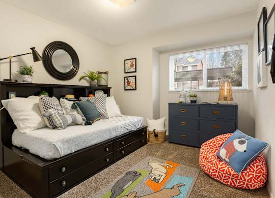 A bedroom with a bed, dresser, and a window with a view of a house.