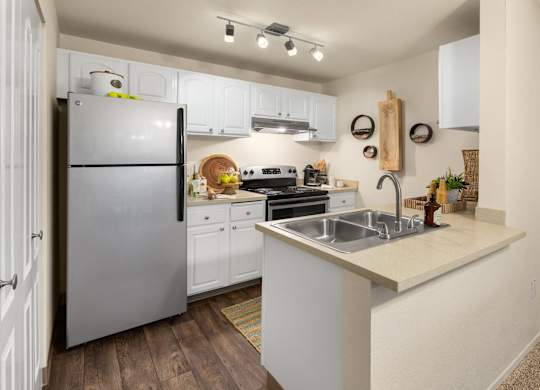 A kitchen with a refrigerator, sink, and stove.
