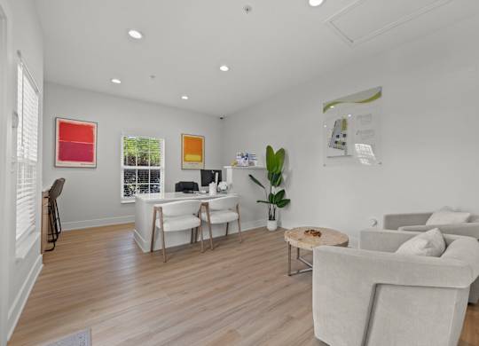 A living room with a grey couch, a coffee table, and a white desk.