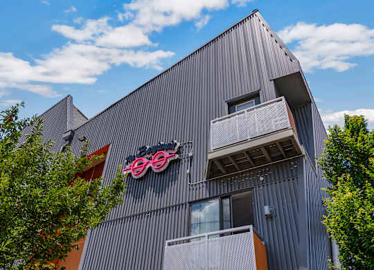 A modern building with a grey facade and a bicycle logo on the side.