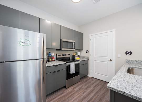 A kitchen with a refrigerator, microwave, oven, and sink.