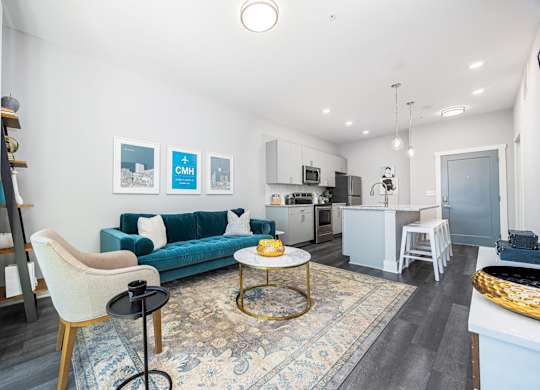 a living room with a blue couch and a kitchen in the background