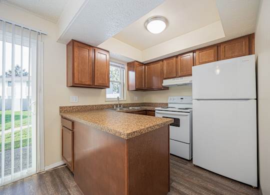 A kitchen with white appliances and wooden cabinets.