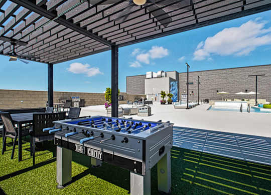 A table soccer table is in the middle of a grassy area.