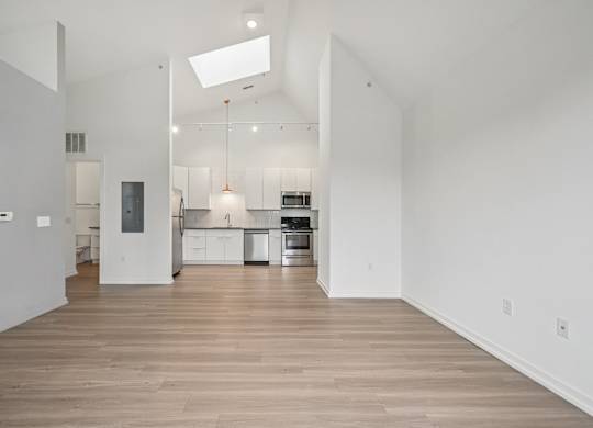 A spacious kitchen with white cabinets and a wooden floor.
