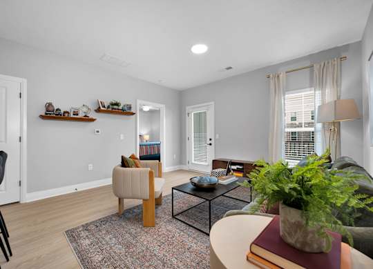 A living room with a couch, chair, and potted plant.