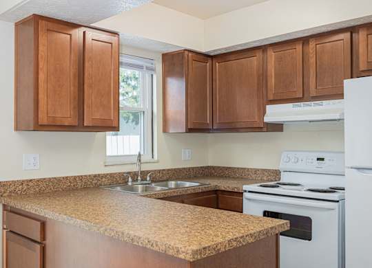 A kitchen with brown cabinets and a white stove.