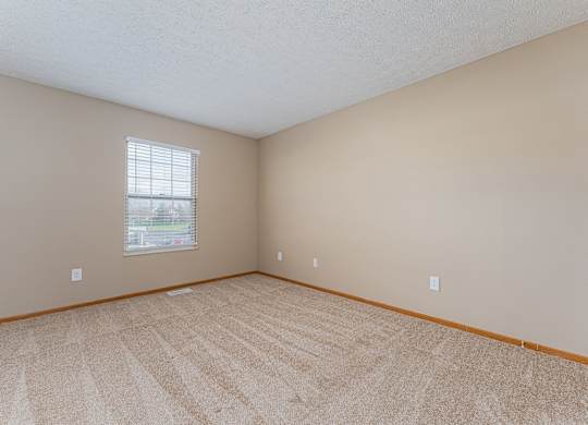 A room with a carpeted floor and a window.