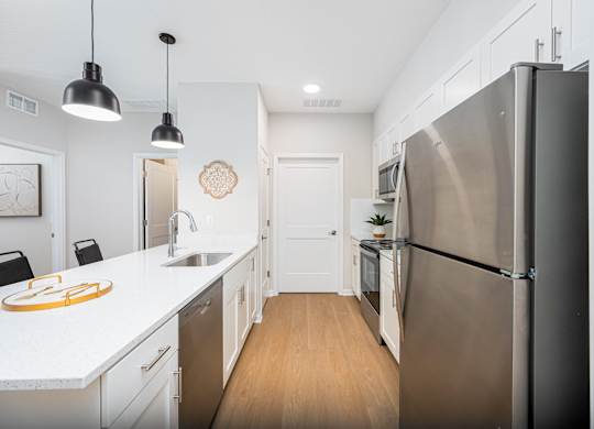A modern kitchen with a stainless steel refrigerator and wooden floors.