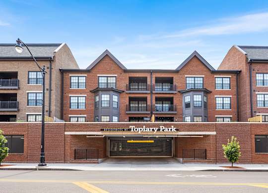 The image shows a multi-story building named Toplary Park with a parking lot in front.