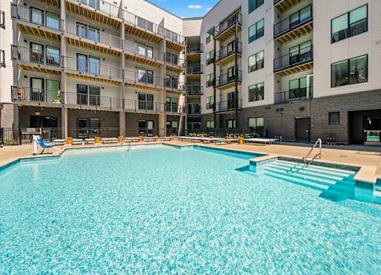 A large swimming pool in front of apartment buildings.