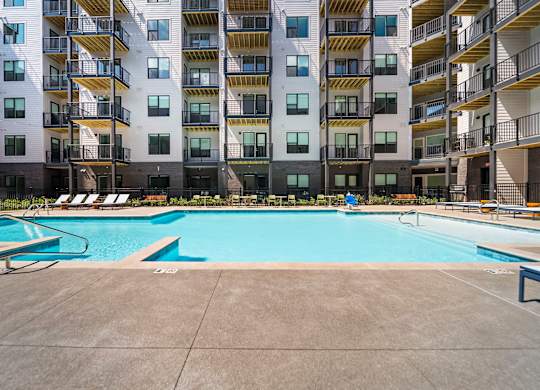 A large swimming pool in front of a multi-story apartment building.
