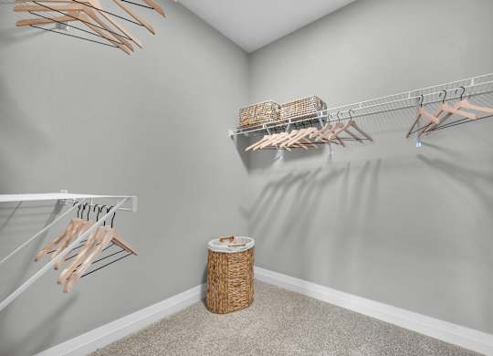A room with a grey wall and a white shelf with clothes hangers.