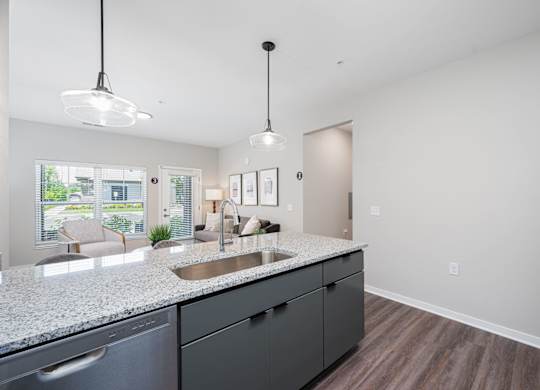 A kitchen with a granite countertop and a refrigerator on the right.