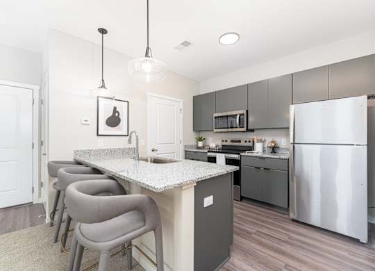 A kitchen with a white counter top and grey chairs.