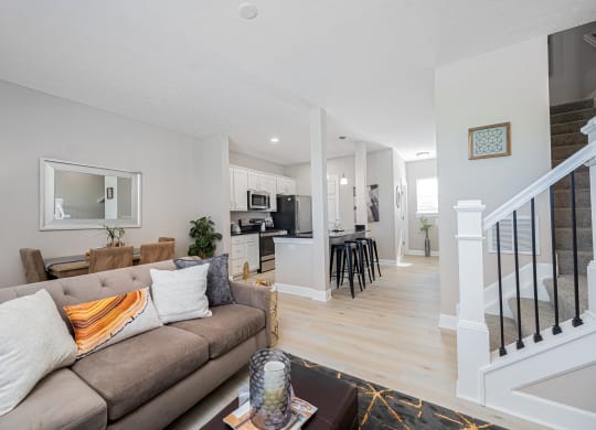 a living room with a couch and a kitchen with a staircase