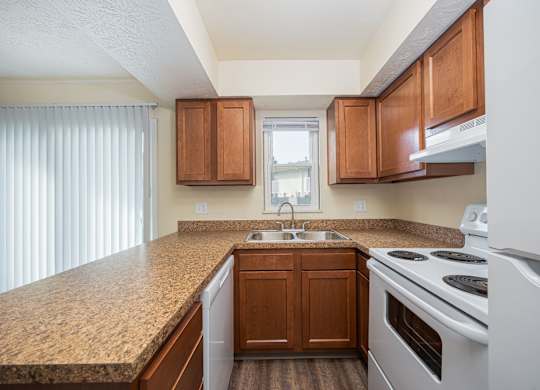 A kitchen with brown cabinets and a white stove top oven.