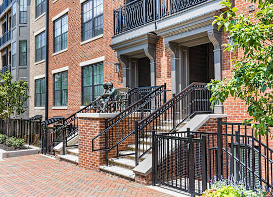 A red brick building with a black railing and steps.