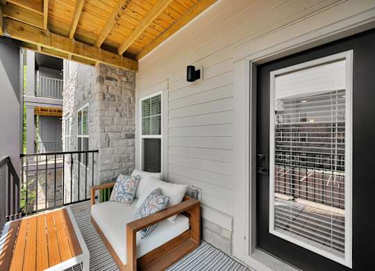 A balcony with a white couch and a wooden table.