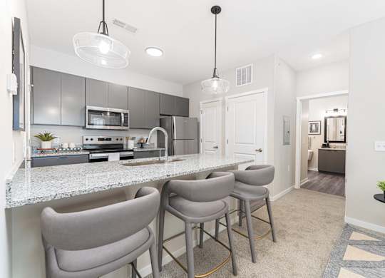 A kitchen with a bar area and grey chairs.