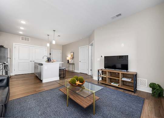 A modern living room with a glass coffee table and a bowl of fruit on it.