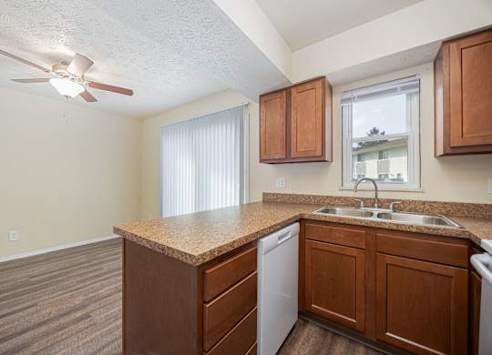 A kitchen with a white ceiling fan and wooden cabinets.