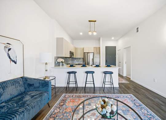 A blue couch is in the corner of a room with a bar and stools.