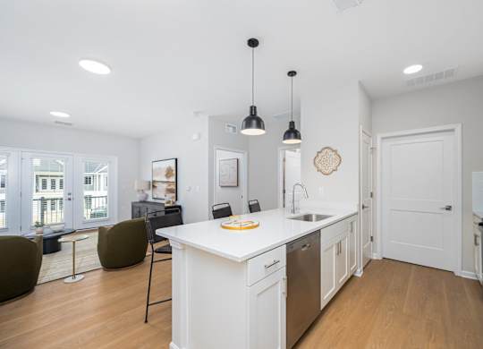 A kitchen with white cabinets and a white island with a sink.