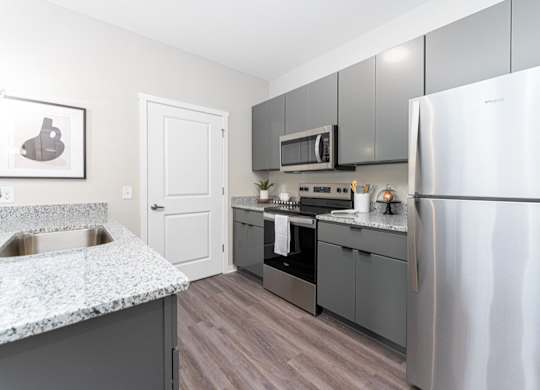 A kitchen with a stainless steel refrigerator, microwave, and oven.