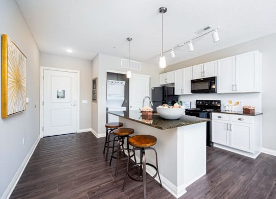 a kitchen with white cabinets and a bar with three stools
