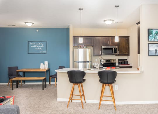 a kitchen with a bar and a living room with a table and chairs