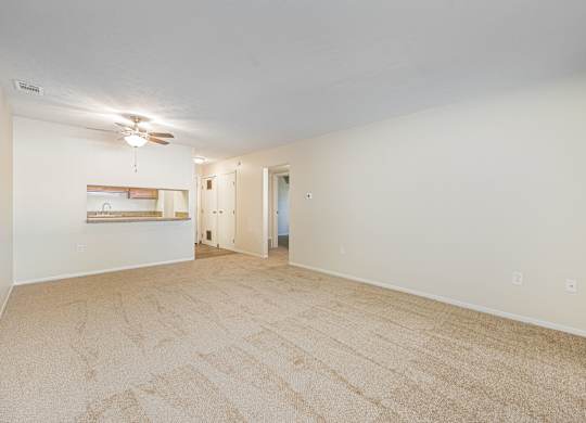 a spacious living room with carpet and a ceiling fan